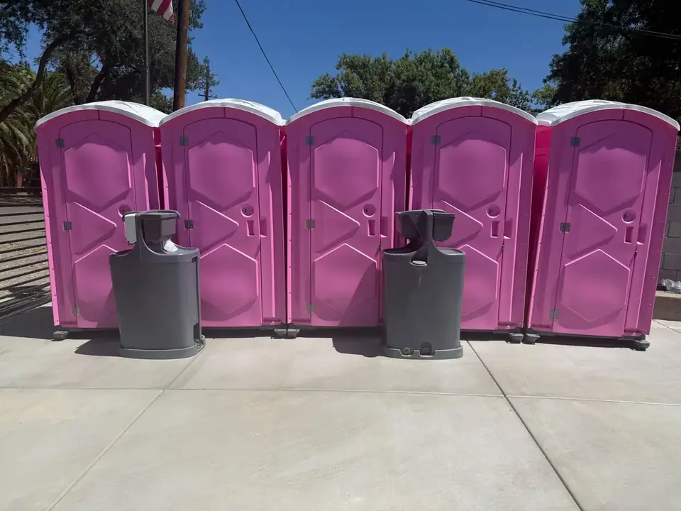 Row of pink event porta potties with hand wash stations on pavement