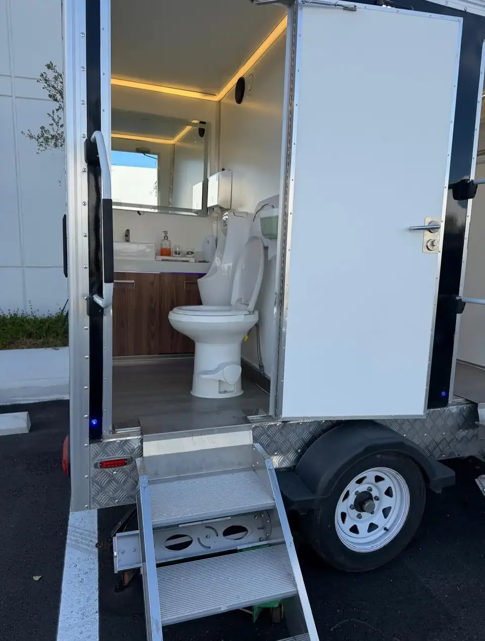 Restroom trailer interior with a wood vanity and lighted mirror