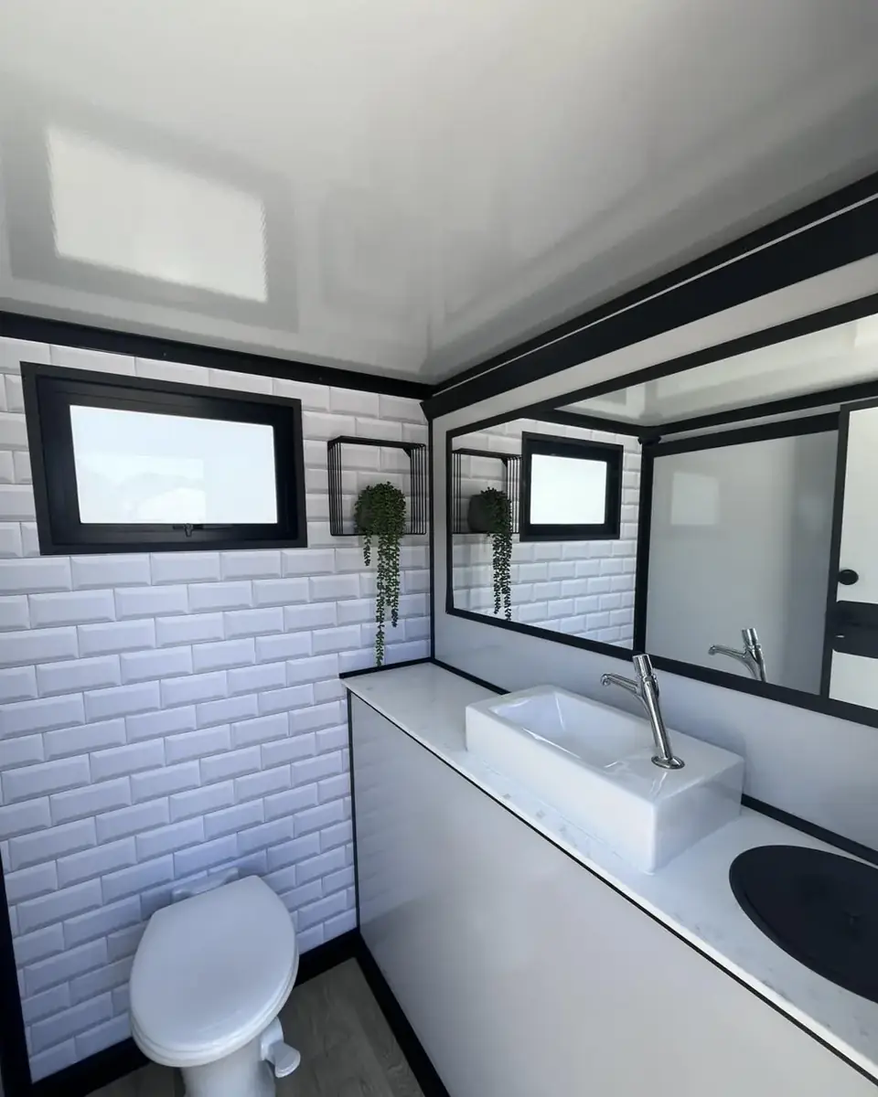 Inside a restroom trailer with a vanity sink, mirror and toilet